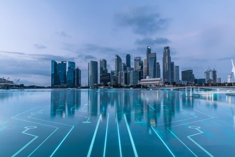 The image showcases a modern city skyline, likely a financial district with tall skyscrapers reflecting in the calm water in the foreground. The water surface is overlaid with digital circuit-like patterns, symbolizing technology and innovation integrated into the urban landscape. The scene suggests themes of digital transformation, finance, or technological advancements within an urban setting, possibly representing the role of technology in enhancing competitiveness within the banking or financial sectors in Southeast Asia. The sky is a soft blue, creating a serene backdrop for the futuristic elements.