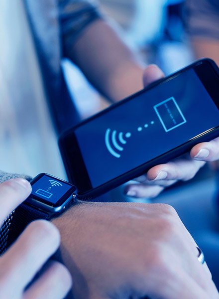 A person transfers funds from their smartwatch to their acquaintance's phone wirelessly